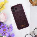 Burgundy rhinestone iPhone case seen from above on white, with yellow and purple flowers and glasses. tbw-rock-cherry-4