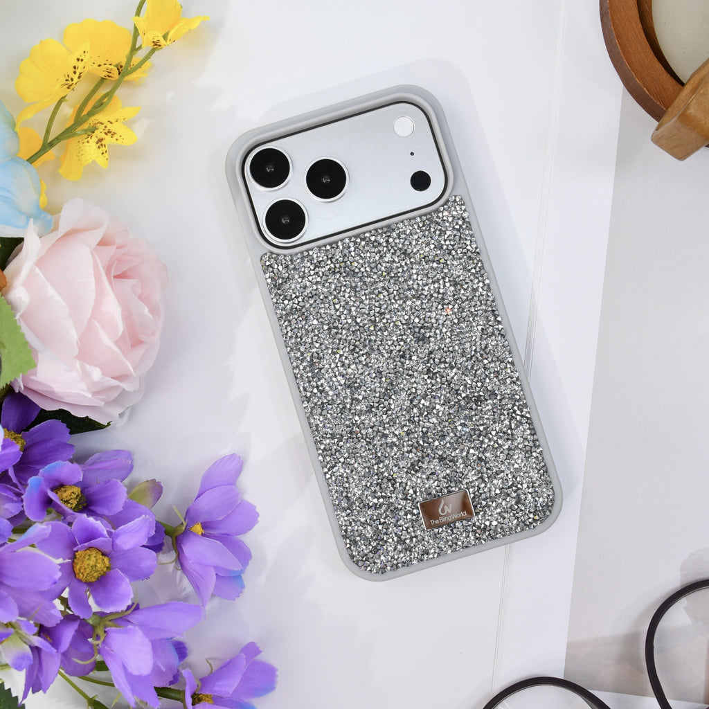 Silver rhinestone iPhone case seen from above on white, with yellow and purple flowers and a wooden cup. tbw-rock-silver-4