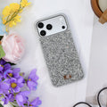 Silver rhinestone iPhone case seen from above on white, with yellow and purple flowers and a wooden cup. tbw-rock-silver-4